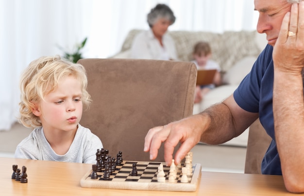 Zdjęcie młody chłopiec gra w szachy z dziadkiem