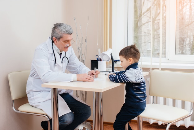 Młody Chłopiec Jest Słuchany I Leczony Przez Doświadczonego Lekarza W Nowoczesnej Klinice. Wirus I Epidemia.