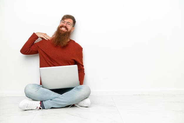 Młody czerwonawo kaukaski mężczyzna z laptopem na białym tle śmiejąc się
