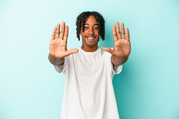 Młody człowiek african american na białym tle na niebieskim tle Wyświetlono numer dziesięć z rąk.