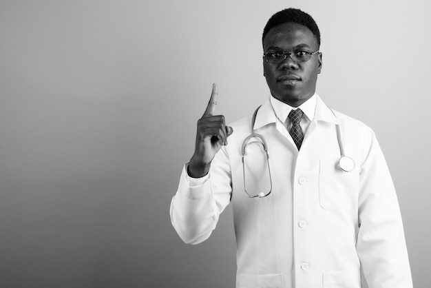 młody człowiek Afryki lekarz noszenie okularów przed białą ścianą. czarny i biały