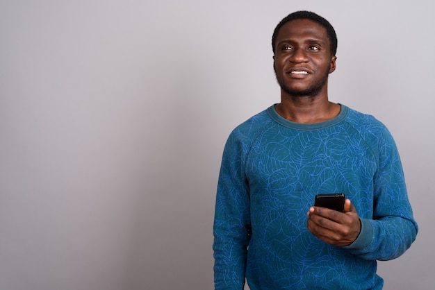 Młody człowiek Afryki przy użyciu telefonu komórkowego na szaro