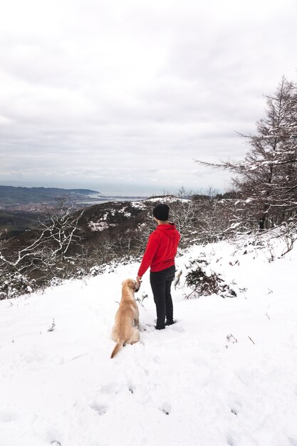 Młody człowiek bawi się z psem na zaśnieżonej górze
