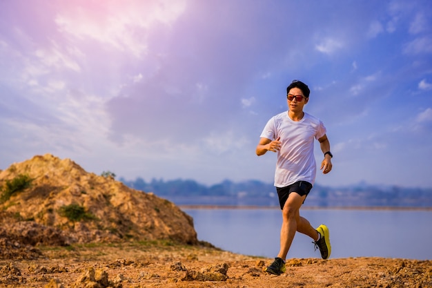 Młody człowiek biegacz biegowy na wschód słońca nad jeziorem Koncepcja zdrowego i stylu życia