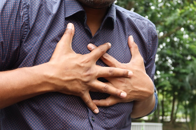 młody człowiek cierpi na ból w sercu i trzymając ręką klatkę piersiową