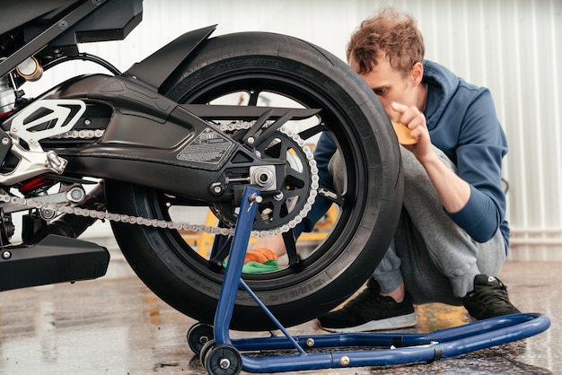 Młody człowiek czyści lub pracuje z nowoczesnym potężnym motocyklem bmw black sportbike