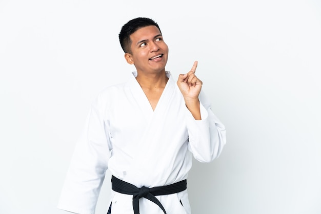 Młody człowiek Ekwadoru robi karate na białym tle z zamiarem realizacji rozwiązania, podnosząc palec w górę