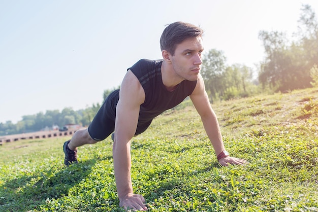 Młody człowiek fitness robi pompki lub deski na plaży