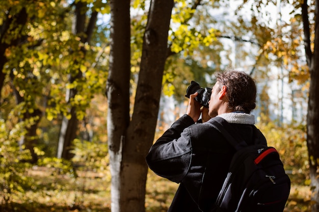 Młody człowiek fotograf w kurtce z plecakiem