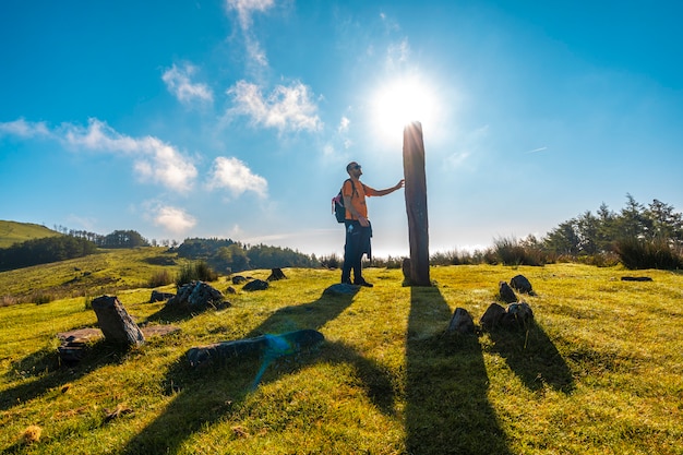 Młody człowiek głaszcze dolmen ze szczytu Monte Adarra w Urniecie, niedaleko San Sebastian. Gipuzkoa, Kraj Basków