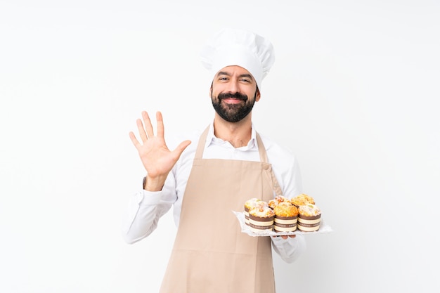 Młody człowiek gospodarstwa muffin ciasto na liczenie pięciu palcami