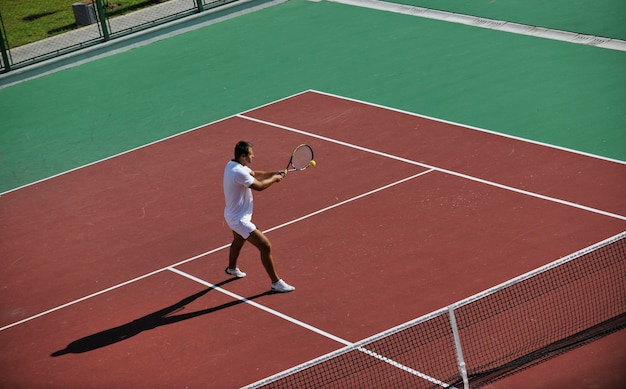 Młody człowiek gra w tenisa.