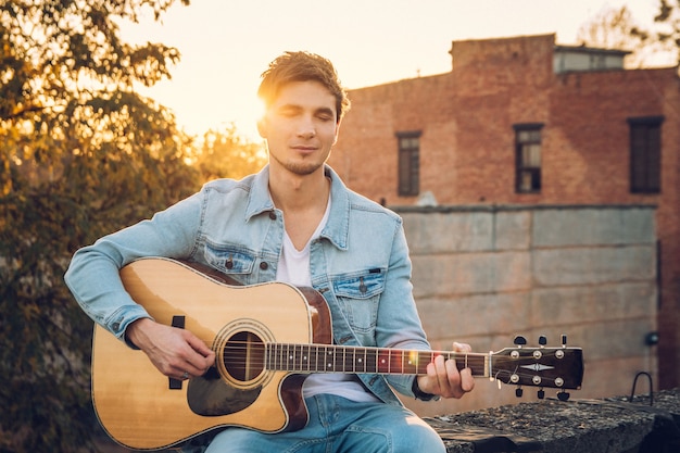 Młody Człowiek Grający Na Gitarze W Mieście Na Tle Promieni Słonecznych