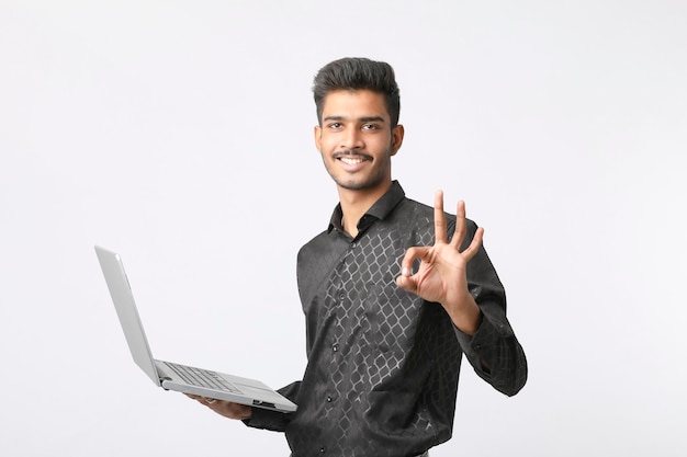 Młody człowiek indyjski za pomocą laptopa na białym tle.