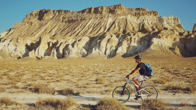 Młody człowiek jedzie bicykl na tle krajobraz z górami