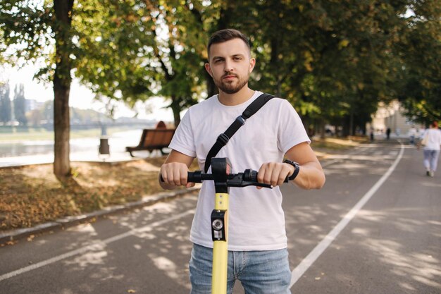 Młody człowiek jedzie na skuterze elektrycznym na spotkaniu ekologicznej koncepcji transportu przystojny mężczyzna