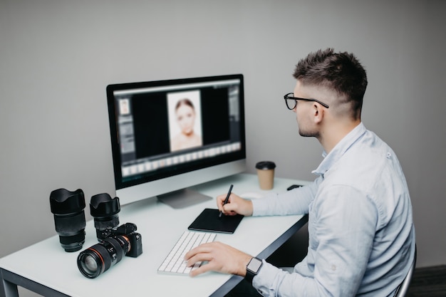 Młody człowiek jest niezależnym fotografem pracującym na komputerze w domu