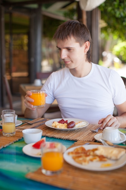 Młody człowiek ma śniadanie w kurort restauraci