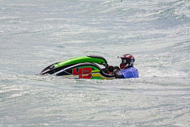 Młody człowiek na skuterze wodnym Zawodowy jeździec na skuterze wodnym Jet Ski Championship Jetski wykonuje wiele sztuczek na falach