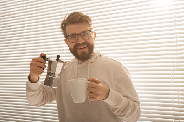 Młody człowiek nalewający kawę z dzbanka moka na poranne śniadanie i koncepcję przerwy