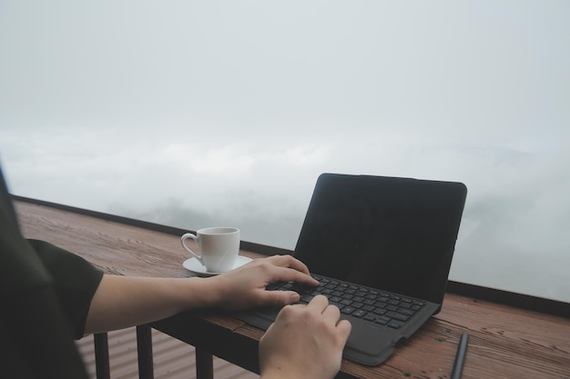 Młody człowiek niezależny podróżnik noszący kapelusz w dowolnym miejscu, pracujący online za pomocą laptopa i cieszący się widokiem na góry