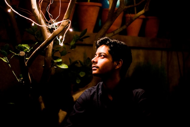 Zdjęcie młody człowiek patrzący na drzewo z oświetlonymi światłami w nocy