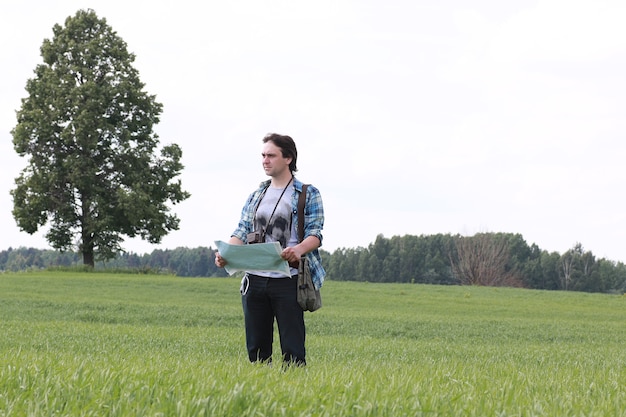 Młody człowiek patrzy na mapę w przyrodzie, aby się nie zgubić