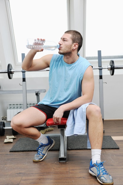 młody człowiek pić wodę na treningu fitness w klubie sportowym