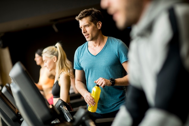 Młody Człowiek Pije Butelkę Woda Na Threadmill W Gym