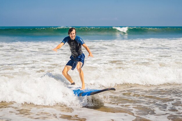 Młody człowiek początkujący Surfer uczy się surfować na morskiej pianie na wyspie Bali