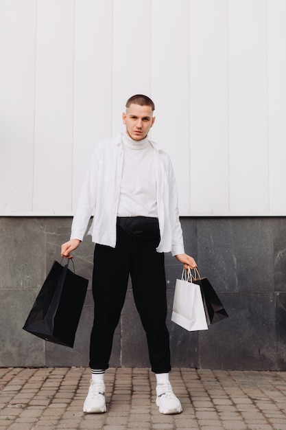 Młody człowiek pozuje z torba na zakupy w Czarny piątek