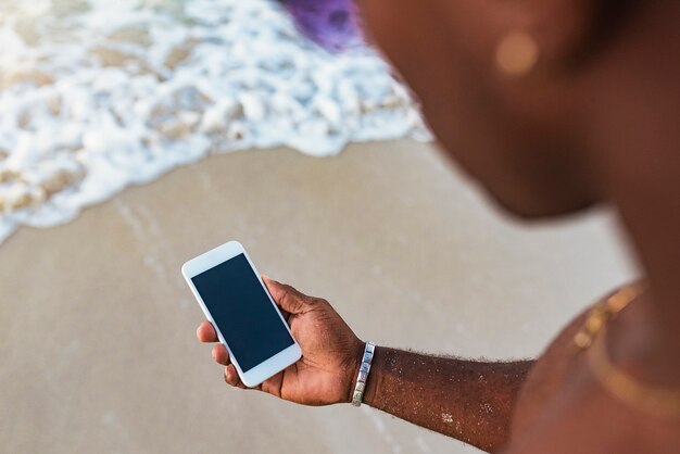 Młody człowiek przy użyciu telefonu komórkowego na plaży. Koncepcja mobilna.