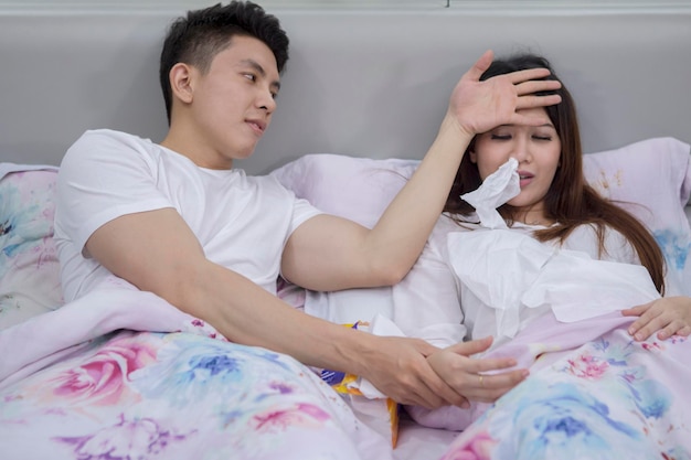 Zdjęcie młody człowiek sprawdza temperaturę swojej chorej żony