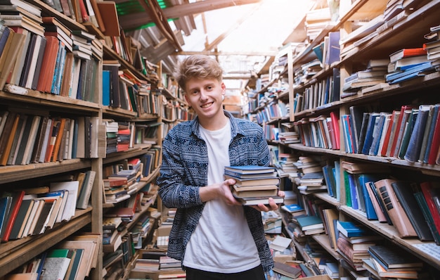 Młody Człowiek Stoi W Starej, Klimatycznej Bibliotece Z Książkami W Ręku