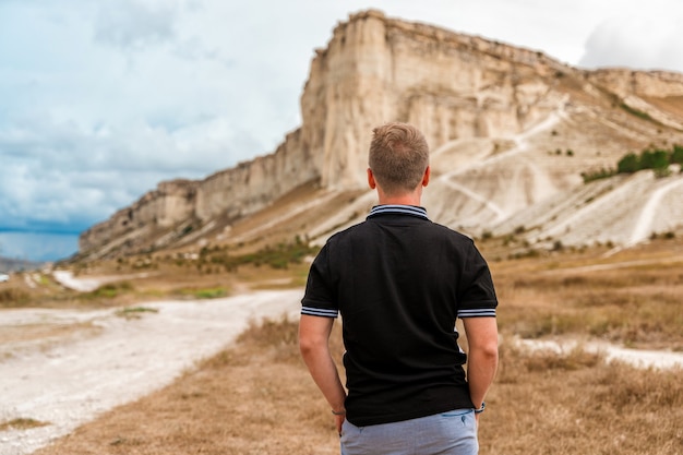 Zdjęcie młody człowiek stojący i patrzący na ogromną białą skałę koncepcję podróży i wolności krym