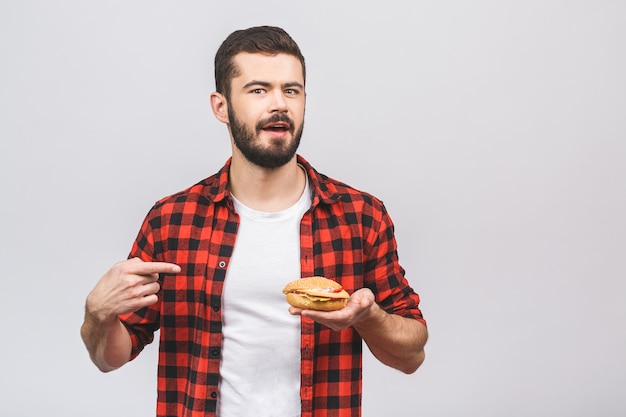 Młody człowiek trzyma kawałek hamburger. Pojęcie diety na białym tle.