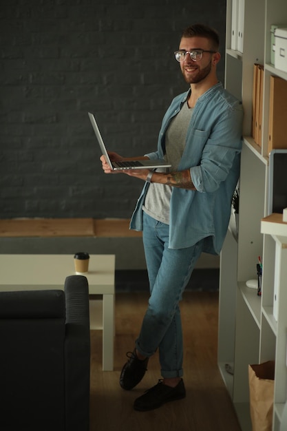 Młody człowiek trzyma laptopa stojącego w pobliżu ściany