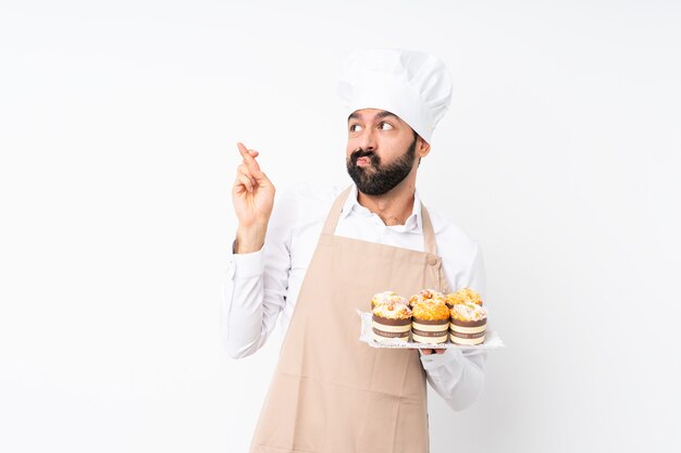 Młody Człowiek Trzyma Tort Muffin Na Pojedyncze Białe Palce Skrzyżowane I życząc Jak Najlepiej