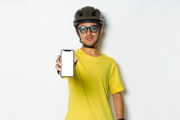 Młody Człowiek Ubrany W Kask Rowerzysty Trzyma Telefon Komórkowy Z Pustym Pustym Ekranem Na Białym Tle