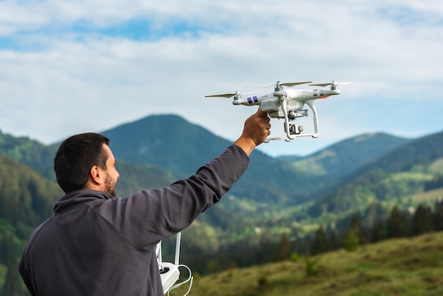 Młody człowiek uruchamia quadrocopter na niebie o charakterze w górach