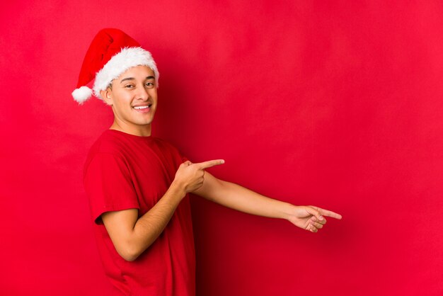 Młody człowiek w Boże Narodzenie podekscytowany, wskazując palcami daleko.