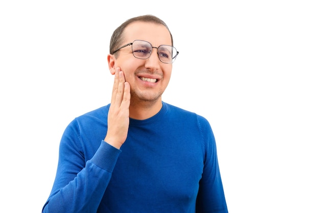 Młody człowiek w okularach cierpiący na ból zęba dotykający policzka na białym tle