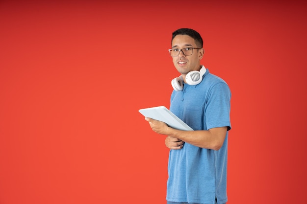 Młody człowiek w okularach na sobie cyfrowy tablet i słuchawki na szyi