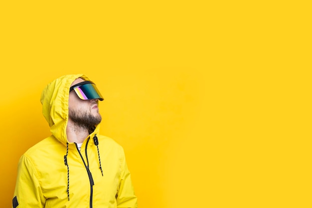 Młody człowiek w okularach wirtualnej rzeczywistości patrzy na żółtym tle