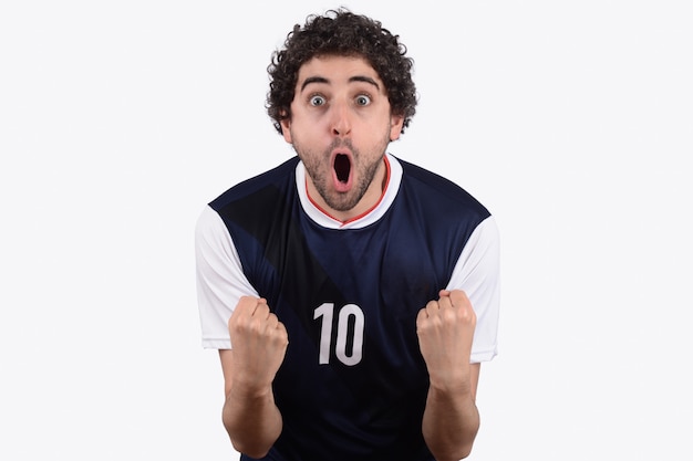 Młody człowiek w piłce nożnej mundur krzyczy podczas gdy jego drużyna wygrywa.
