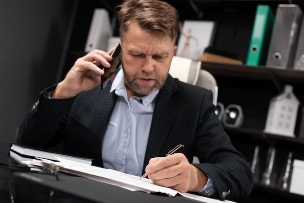Zdjęcie młody człowiek w ubrania biznesowe pracuje przy komputerze biurko z telefonem i dokumentami