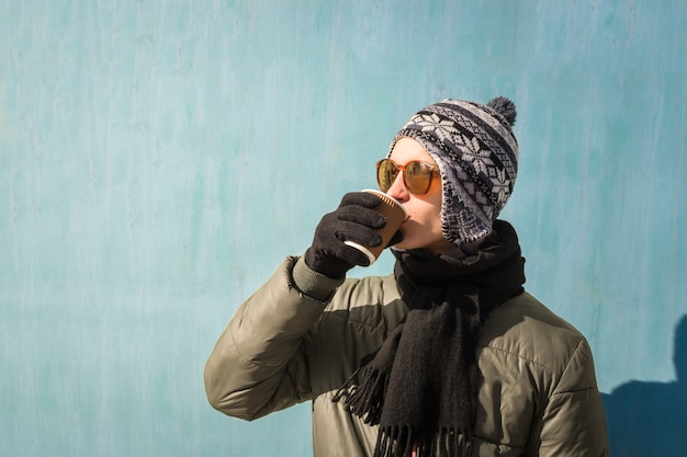 Zdjęcie młody człowiek w zimowe ubrania trzyma filiżankę kawy