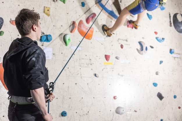 Młody człowiek wspinacz ceratyny na ścianie wspinaczki centrum aktywności sportowej koncepcji