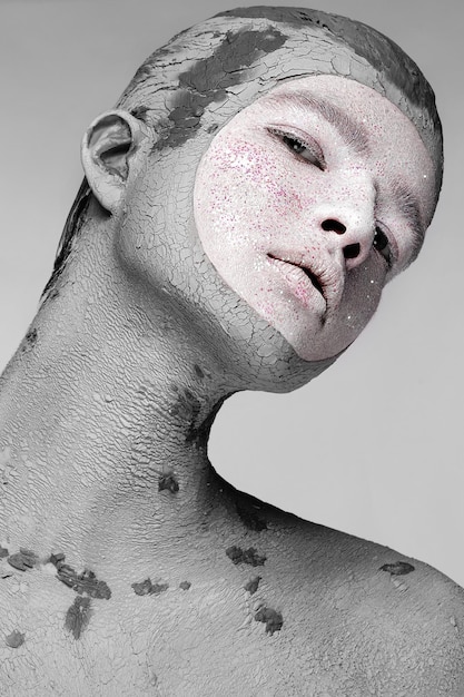 Młody człowiek z artystycznym kreatywnym makijażem z błotem na twarzy Kosmetyczna maska Piękna twarz Zdjęcie zrobione w studio na czarnym tle