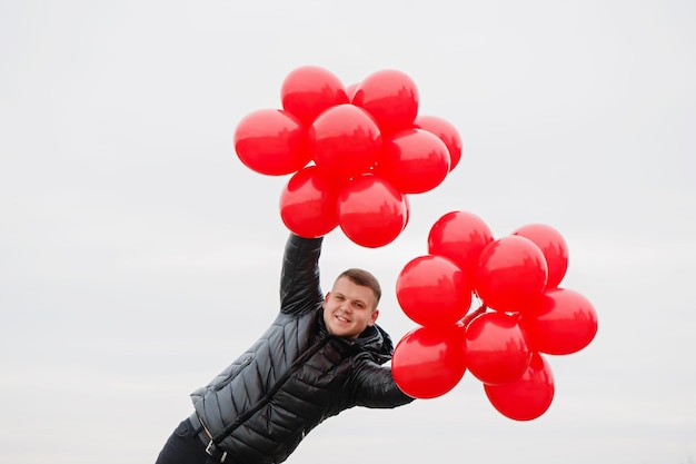 Młody Człowiek Z Czerwonymi Balonami W Jego Rękach. Pomysł Na Walentynki